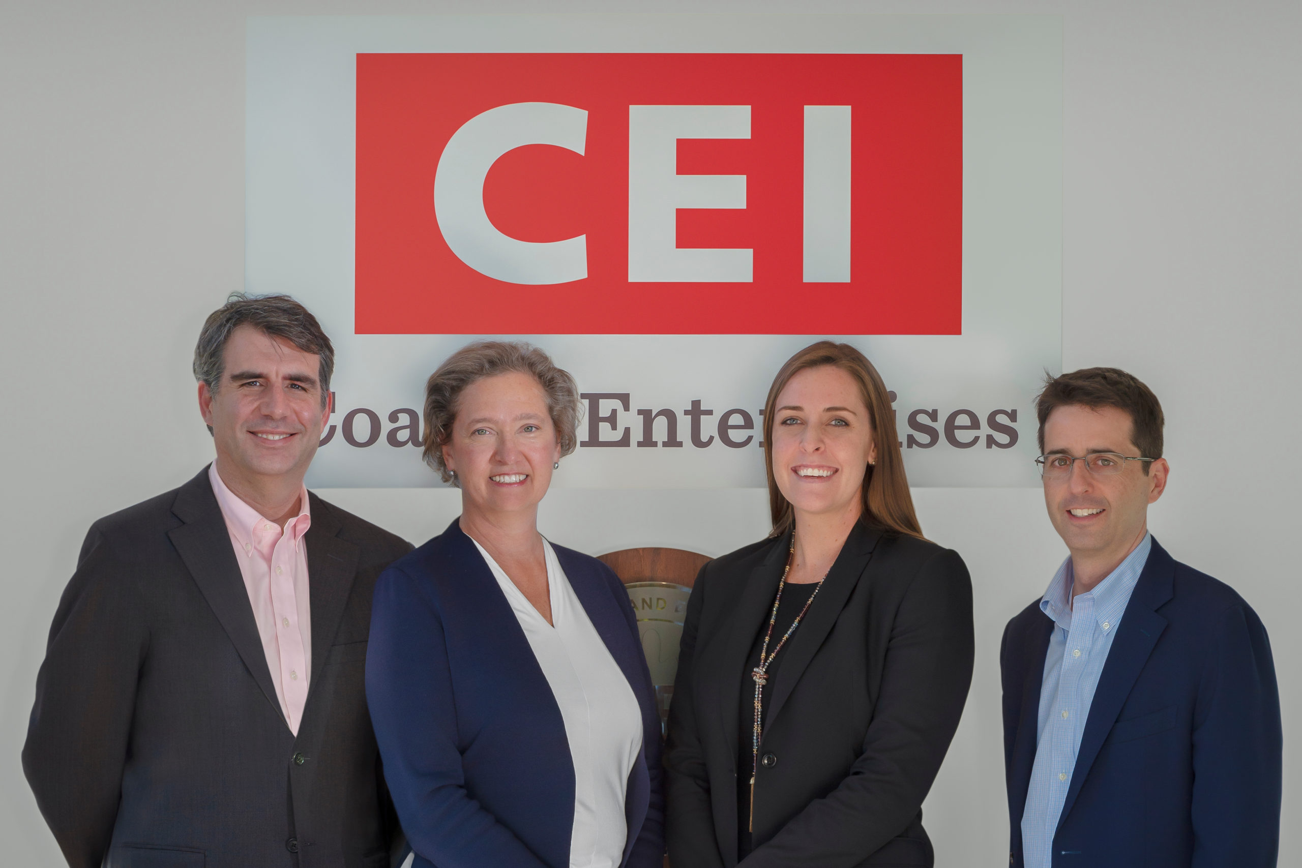 Representative of CEI and Woodforest National Bank stand in front of the CEI Sign