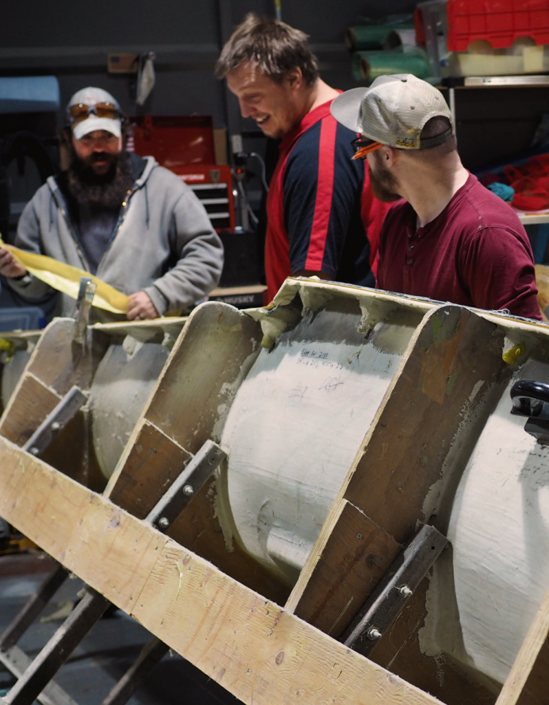 Three men work on a large composite mold