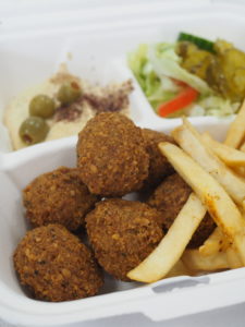 A takeout container of falafel and fries