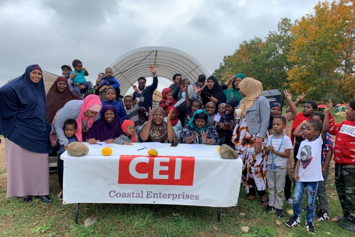 A group of Somali immigrant women and their families celebrate behind a table with the CEI logo