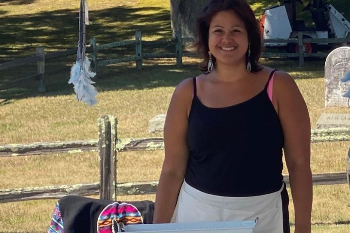 A smiling Passamaquoddy Native American woman standing in front of a craft fair booth